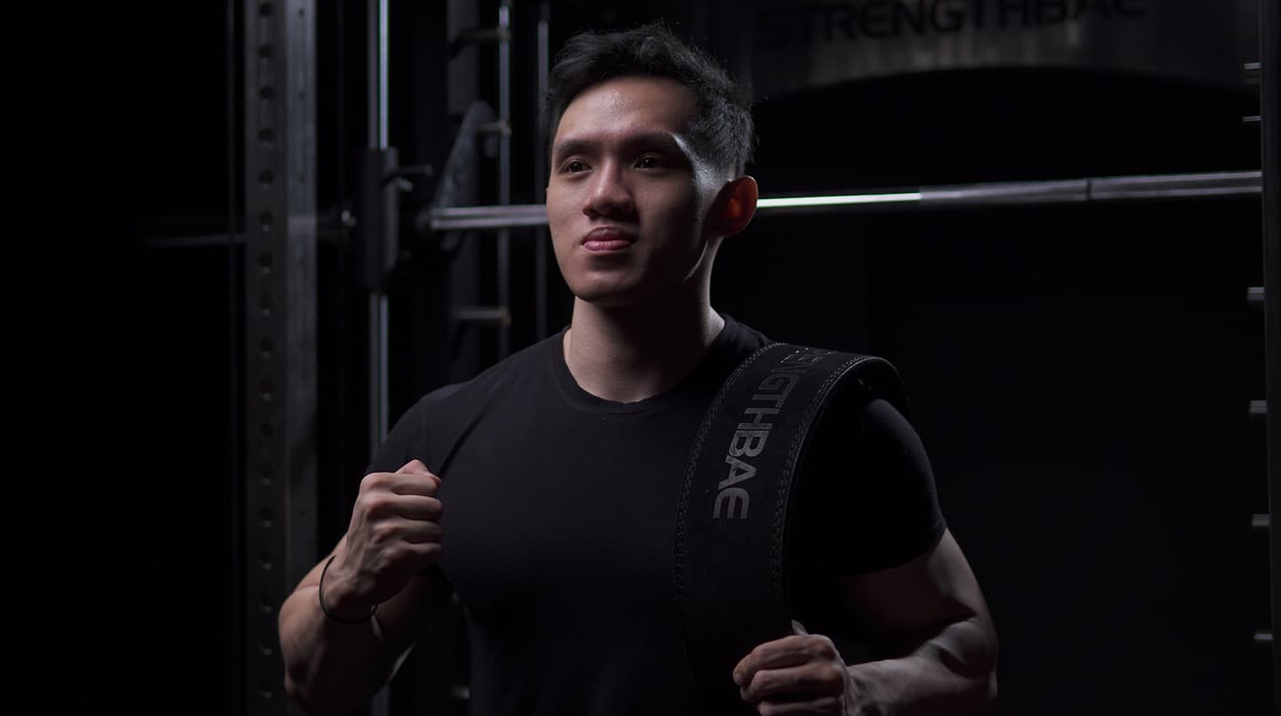 Athlete carrying a Strengthbae strap in a dark gym